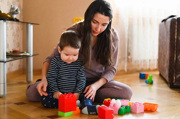 Mamma utvecklar sitt barn med leksaker. Den framtida byggmästaren. Pojke och mamma leker med en leksak — Stockfoto
