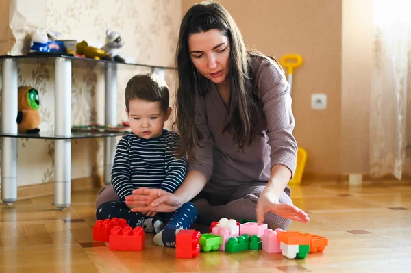 Mamma utvecklar sitt barn med leksaker. Den framtida byggmästaren. Pojke och mamma leker med en leksak — Stockfoto