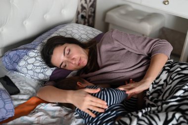 Anne ve bebek mutlu bir şekilde uyur. Annem uyurken bebeğine gülümser. Anne ve bebeğin sakin rüyası.