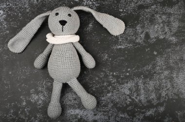 Koyu bir arka planda gri örülmüş tavşan. Siyah Paskalya konsepti. Siyah yumurtalar. Siyahlar için Paskalya.