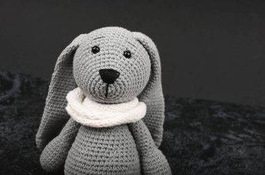 Koyu bir arka planda gri örülmüş tavşan. Siyah Paskalya konsepti. Siyah yumurtalar. Siyahlar için Paskalya.