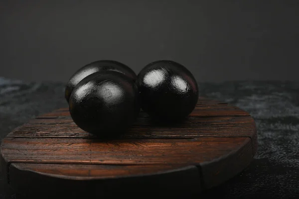 Huevos negros en una tabla de madera. Acostado. Pascua Negra. tres huevos negros — Foto de Stock