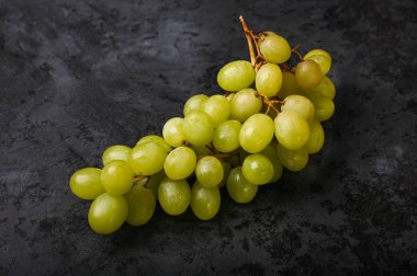Mermer bir arka planda bir demet yeşil üzüm. Volumetrik şaraphane. Bir demet yeşil üzüm çalısı.