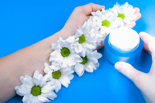 Top view and flat lay of a woman holding a cream in her hands over a blue background. Natural creams for healthy skin. Natural cosmetic. The concept of natural medicine. Eco medicine. flat lay
