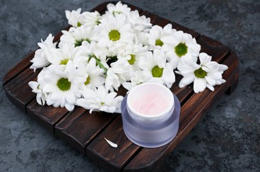 Doğal kozmetik konsepti. Çiçekler ve bir kavanoz krema. Kalp şeklinde papatyalar ve bir kavanoz krema. Yukarıdan bak. Doğal kozmetik. Kaydedilecek yer.