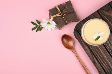 Pembe arka planda cilt bakım kremi. İçinde güzel bir gül olan bir kavanozda krema. Yaşlanma karşıtı krem. Cilt bakımı için krem. Eller için. Yüz için. Bakım için kozmetik