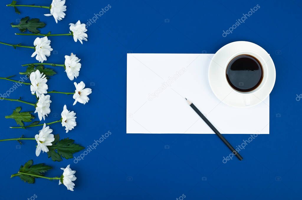 White chrysanthemums with paper card note on blue background. To do list consept. Floral pattern.
