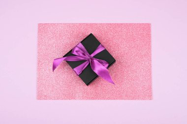 Pembe arka planda hediye paketi. Yukarıdan bak. Düz yat. Fiyonklu siyah ambalaj. Kara Cuma. Çeşitli arkaplan