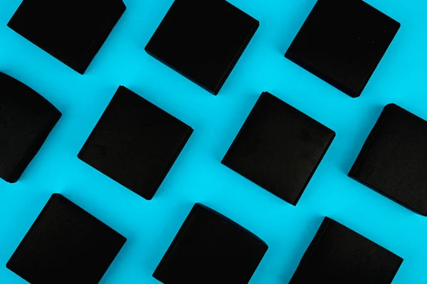 black boxes on blue. black boxes on a blue background on a flat lay. Black square on blue. black cubes flow.