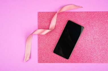 Telefon pembe arka planda. Pembe kurdele.