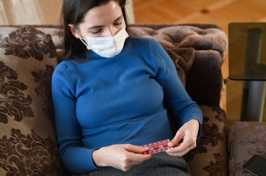 Corona virüsünden korumak için maskeli bir kız. Koronavirüs salgını. Bir sürü beyaz hap alan bir kadın. Kapat..