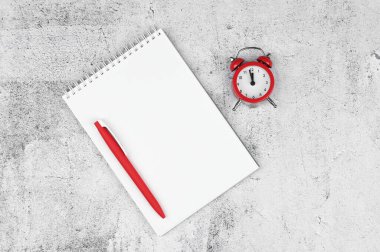 Time management concept. To-do list: red alarm clock, pencil and notebook.