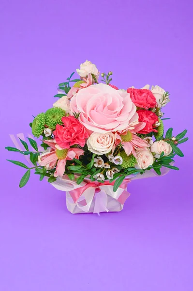 Bouquet of flowers in pink packaging on a purple background. Congratulations to the women. Flowers are loved