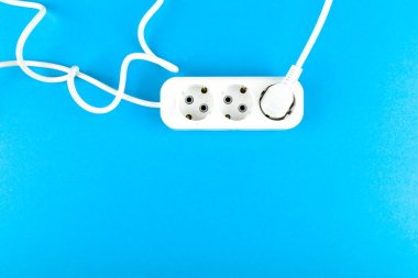 Kablolu beyaz soket. Yukarıdan bak. Mavi bir arka planda. Beyaz soket ve uzatma kablosu. Uzun spiral kablosu olan üç priz için uzatma kablosu