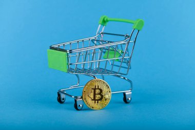 Alışveriş arabasında Bitcoin. Mavi arka planda. bir yazıt için yer