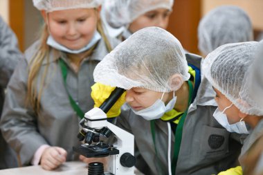 Mikroskop ve çocuklar. Tıp önlüklü çocuklar mikroskopla bakıyorlar. Tıp öğretiyorum. Hastanedeki bir seminerde genç doktorlar. KHARKIV, UKRAINE - 20 HAZİRAN 2020.