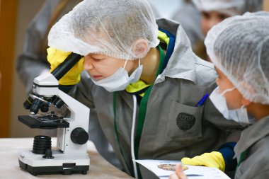Bebek mikroskoptan bakıyor. Tıp öğretiyorum. Hastanedeki bir seminerde genç doktorlar. Çocuk ve tıp KHARKIV, UKRAINE - 20 HAZİRAN, 2020.