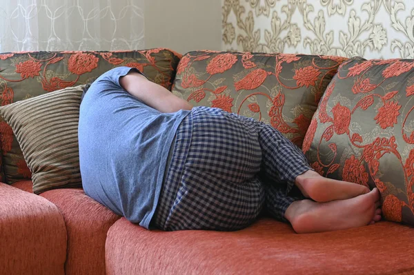 Man is lying on the couch in depression. lying on the couch in the fetal position