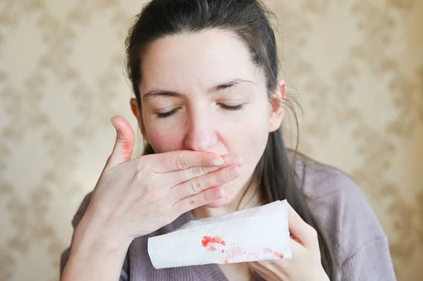 Close-up of a young woman with fear watches the blood on her napkin. Sick person concept