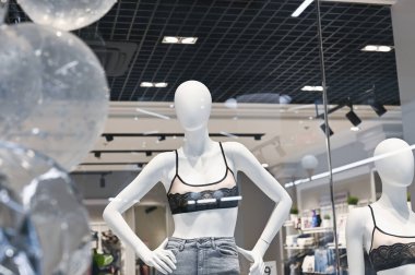 Beyaz manken camın arkasında yeni giysiler gösteriyor..