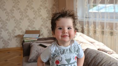 Neşeli kıvırcık çocuk kameraya bakıyor..