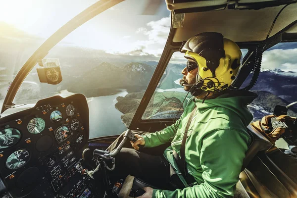 Helikopter pilotu. Helikopter pilotu. Helikopter, dağlar ve okyanus üzerinde uçuyor. Güneşli bir gün. Helikopterin içinden bak..