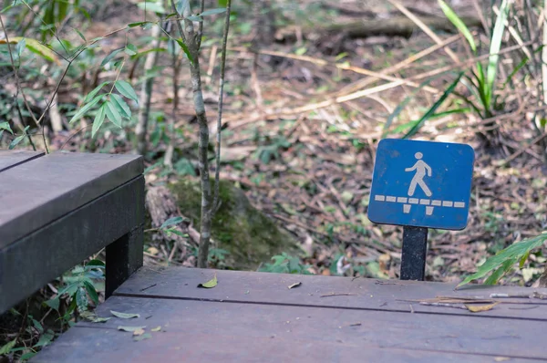 Walking trail signpost, sign of human walking along the bridge to directioning people to walk along the wooden bridge trail.