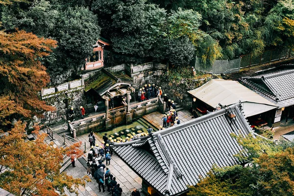 2019年11月11日 黄色の小屋を着た日本人学生が京都の清水寺で聖水を飲むのを待っています — ストック写真