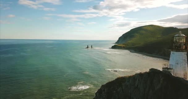 Langsam fliegen in der Nähe felsigen Klippe mit Leuchtturm. Meeresküste ist auf background.Russia — Stockvideo
