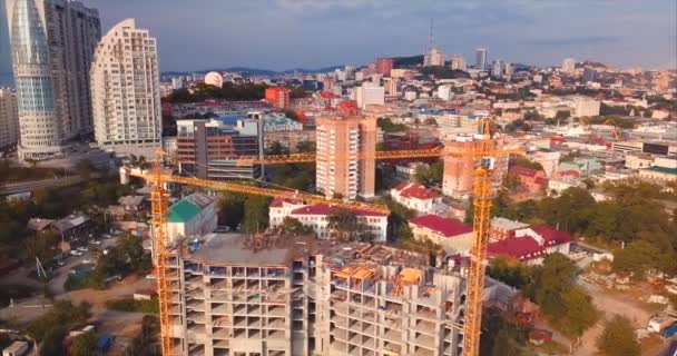 Aerial descending view of house under constaction, working cranes in city center — Stock Video