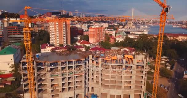 Aerial ascending view of house under constaction, working cranes in city center — Stock Video