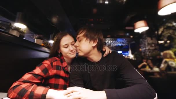 Пара целуется в ресторане и смотрит в камеру счастливо улыбаясь — стоковое видео