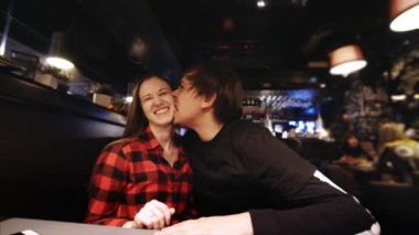 Adam onun girlfiend bir yanağına ısırıyor, her ikisi de bir restoranda eğleniyor musun