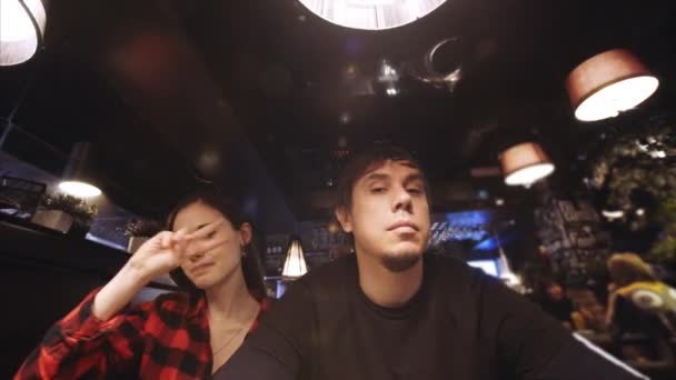 Paar amüsiert sich im Café, macht lustige Gesichter in die Kamera, tanzt, lacht — Stockvideo