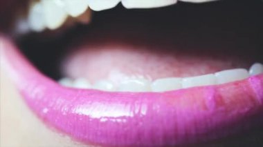 Şehvetli kadın dudaklar. Mor parlak dudaklar, beyaz dişler ve kadının gülümseme.