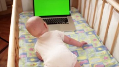 Şirin bebek çocuk crowling chromakey ekran ile dizüstü bilgisayara, üst ağır çekim