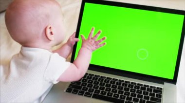 6 ay eski erkek bebek yatakta laptop önünde chroma anahtar perde ile yatıyor