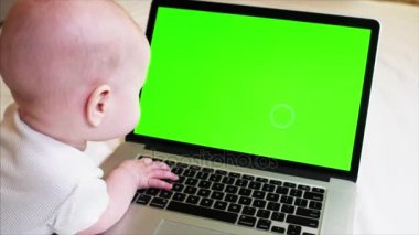 6 ay eski erkek bebek yatakta laptop önünde chroma anahtar perde ile yatıyor