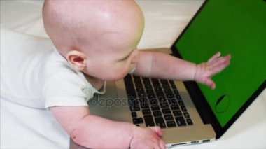 6 ay eski erkek bebek yatakta laptop önünde chroma anahtar perde ile yatıyor