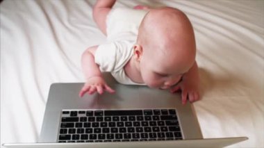 Yatakta yatan ve dizüstü bilgisayar ile oynamak çok güzel 6 ay bebek çocuk portresi