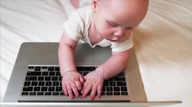 Yatakta yatan ve dizüstü bilgisayar ile oynamak çok güzel 6 ay bebek çocuk portresi