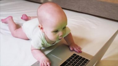 Yatakta yatan ve dizüstü bilgisayar ile oynamak çok güzel 6 ay bebek çocuk portresi