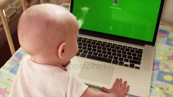 Retrato em câmera lenta de menino de 6 meses brincando com laptop em sua cama — Vídeo de Stock