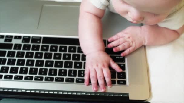 Porträtt av bedårande 6 månader baby pojke ligger i sängen och leker med laptop — Stockvideo
