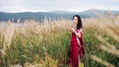 Renkli elbiseli çekici çingene kadın çimenli pipo içiyor. 