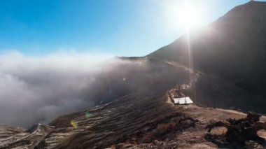 Krater boyunca yürüyen turistlerin zaman akışından uzaklaşıp içinden asit dumanları çıkan Ijen volkan kalderasını keşfediyorlar. Doğu Java, Endonezya