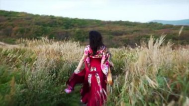 Mutlu esmer çingene kadın gitarıyla sahada koşuyor ve dans ediyor. 