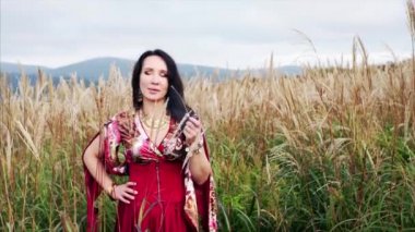 Renkli elbiseli çekici çingene kadın çimenli pipo içiyor. 