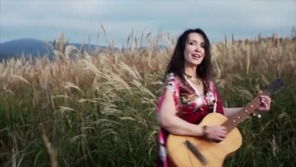 Bela Mulher Cigana Vestido Longo Tocando Guitarra Cantando Entre Grama — Vídeo de Stock