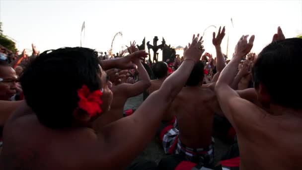 Bali Indonesia 2019年7月10日 伝統的なケチャック舞踊を披露しながら 耳の後ろに赤い花を持つ無数のインドネシア人男性が動いて歌います — ストック動画
